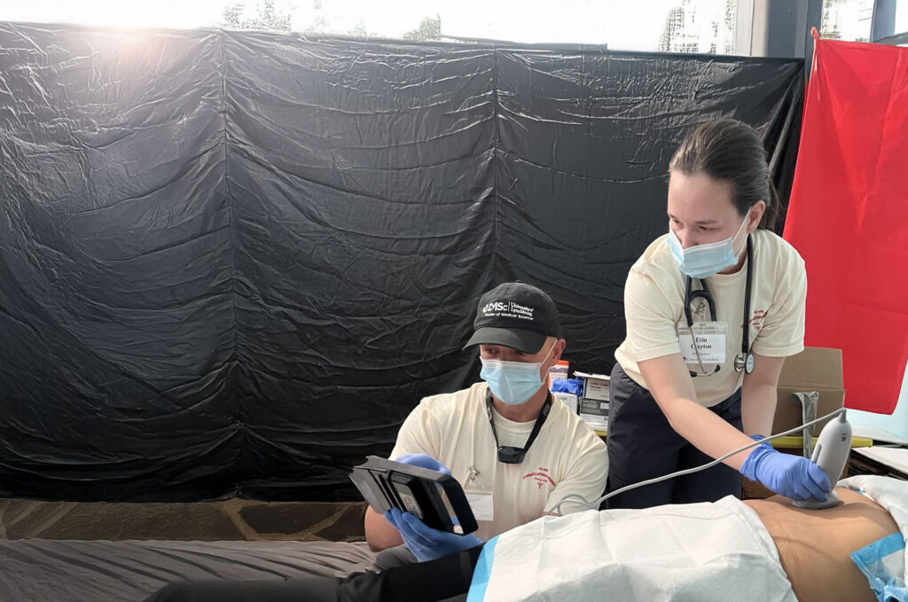 Two clinicians provide patient care during medical missions using portable equipment