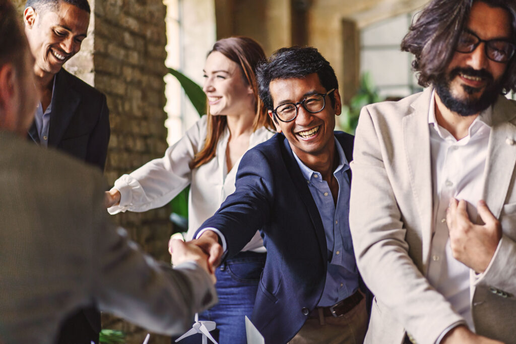 Relationship Building in the Workplace as colleagues smile and shake hands during a meeting.