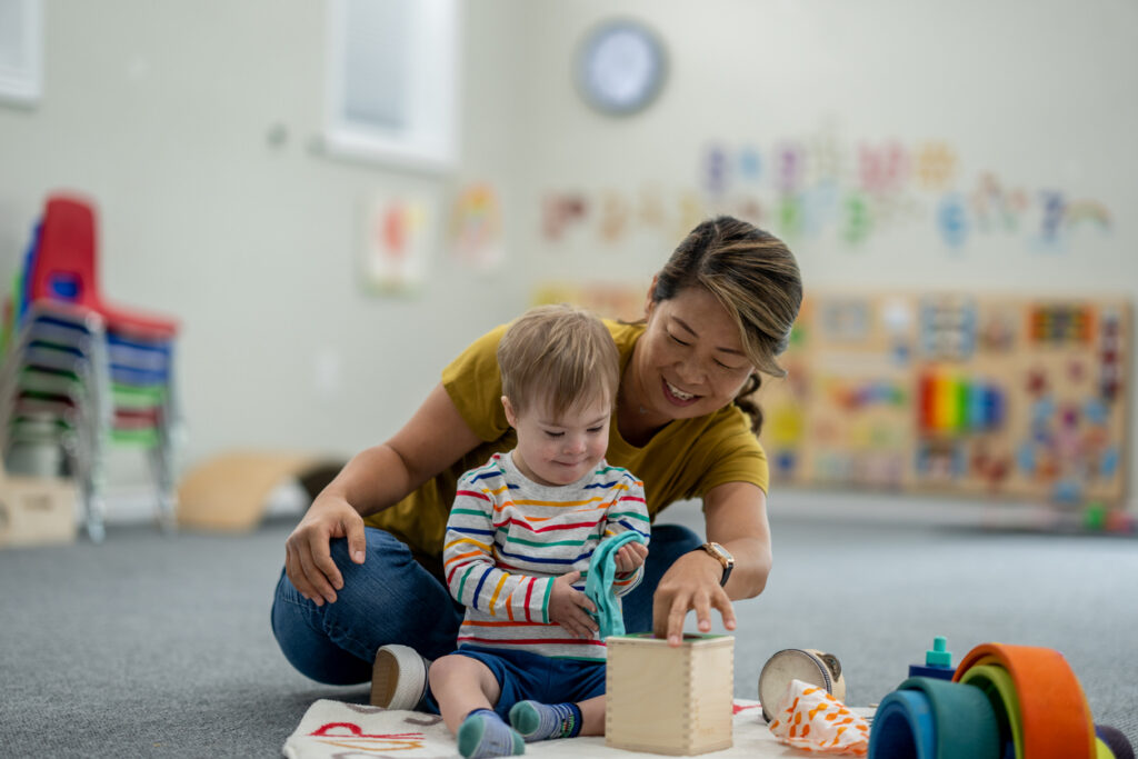 Teacher supporting a young child during a hands-on learning activity illustrating early childhood support in the history of special education.